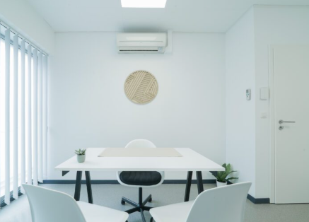 Une table de travail dégagée et deux sièges visiteurs dans un bureau lumineux.